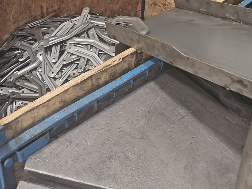 Crate of stamped parts beside the press tooling bench