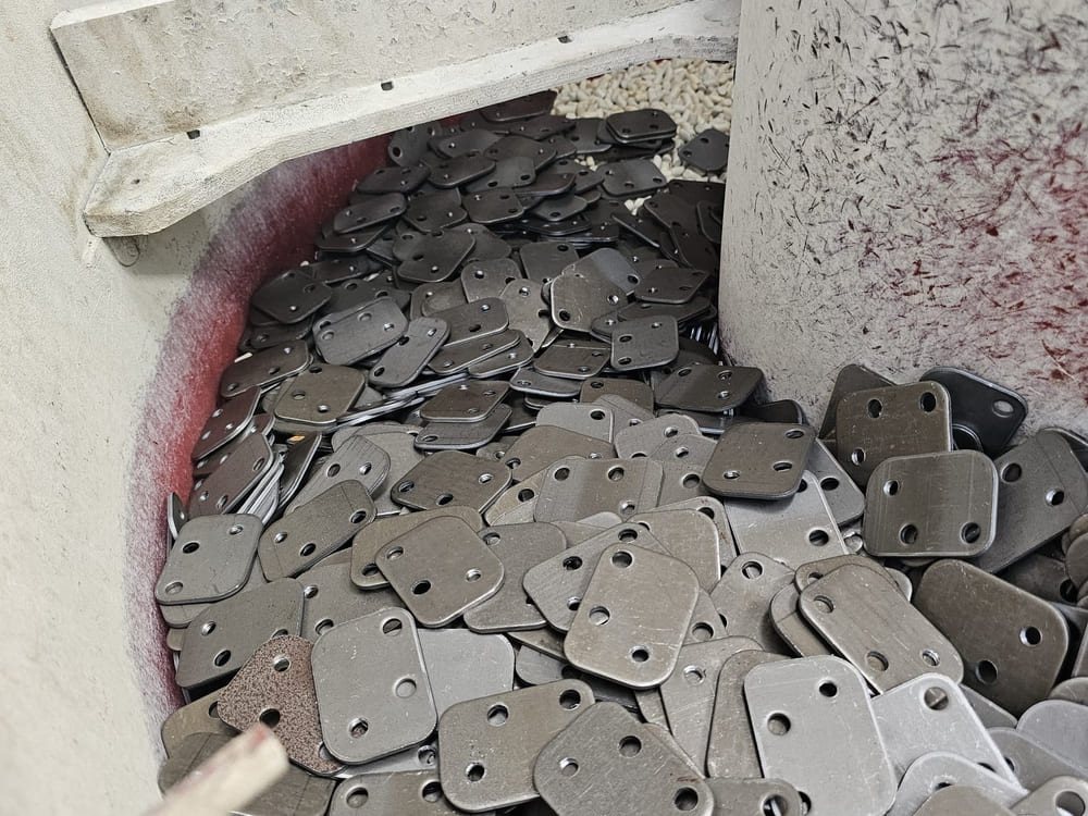 Stamped connecting plates being deburred in the vibratory bowl