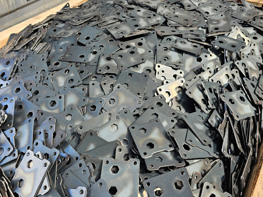 Black-coated connecting plates stacked in a timber crate